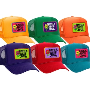 May include: Six colorful trucker hats with mesh backs. Each hat features a rectangular patch with a flower and the text "HAVE A NICE DAY". Colors include orange, green, red, blue, and teal.