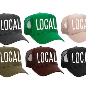 May include: Six trucker hats in different colors with the word "LOCAL" in white lettering on the front.