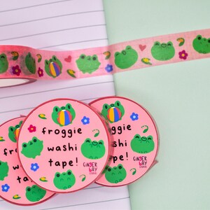 May include: Four rolls of pink washi tape with a frog and ball design. The tape is labeled "froggie washi tape!" and "Ginger Bay Stickers".