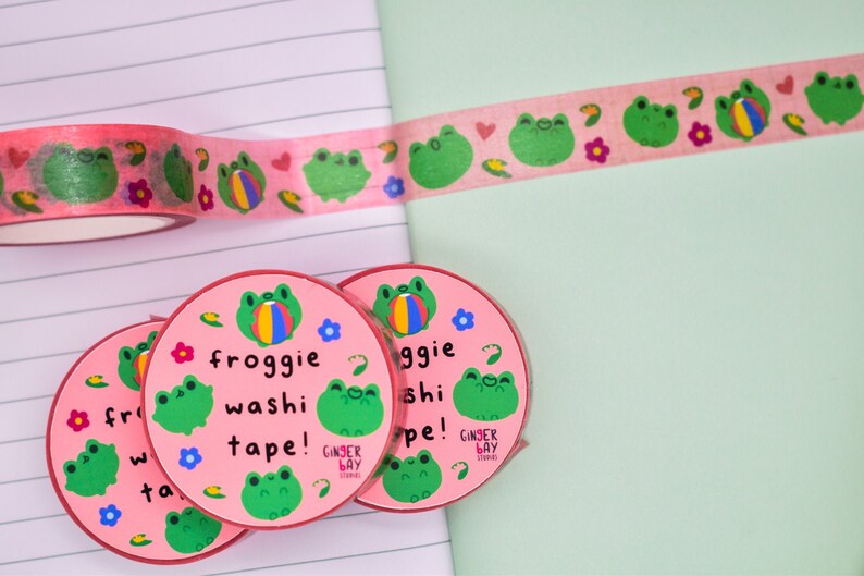 May include: Four rolls of pink washi tape with a frog and ball design. The tape is labeled "froggie washi tape!" and "Ginger Bay Stickers".