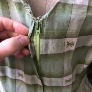 Op de afbeelding: Een groene en witte geruite jurk met een rits. De jurk heeft een klein geborduurd ontwerp op de stof.