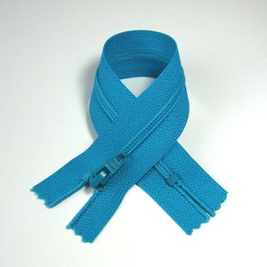 May include: A turquoise zipper with a plastic slider. The zipper is folded in half and the ends are overlapping.