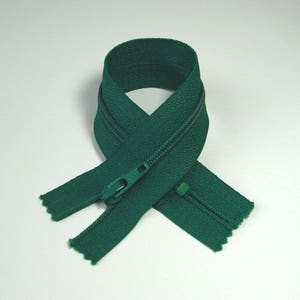 May include: A green zipper with a metal slider. The zipper is closed and folded in half.