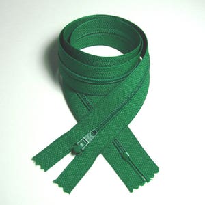 May include: A green zipper with a metal slider. The zipper is folded in half and tied in a knot.