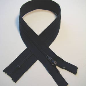 May include: Black zipper with a silver pull tab, shown in a looped configuration. The zipper tape is a solid black color. The zipper teeth are visible and metallic. Ideal for sewing projects, clothing repair, and crafting.