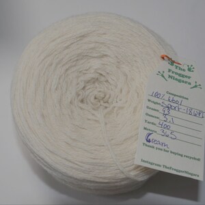 May include: A skein of cream-colored wool yarn, labeled as 100% wool, Sport weight, 18 WPI. The label also includes the weight in grams (93), ounces (3.1), yards (400), and meters (365).