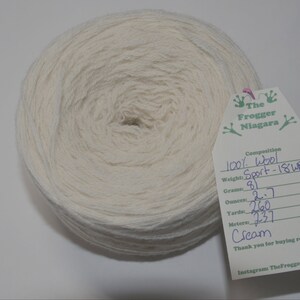 May include: A skein of cream-colored 100% wool yarn labeled "Sport - 18WPI" with a weight of 81 grams, 2.7 ounces, 260 yards, and 237 meters. The label also includes the text "The Frogger Niagara" and "Thank you for buying recycled!"