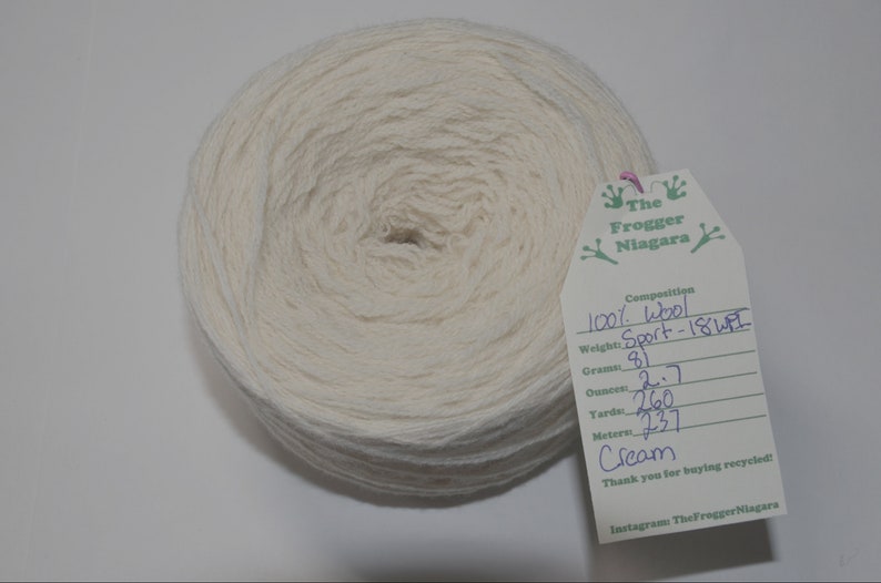 May include: A skein of cream-colored 100% wool yarn labeled "Sport - 18WPI" with a weight of 81 grams, 2.7 ounces, 260 yards, and 237 meters. The label also includes the text "The Frogger Niagara" and "Thank you for buying recycled!"