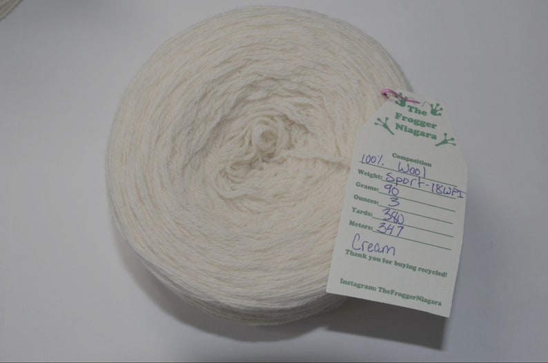May include: A skein of cream-colored wool yarn, labeled as 100% wool, Sport-18WPI, weighing 90 grams (3 ounces), with 380 yards (347 meters).
