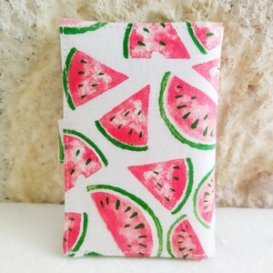 May include: A white fabric pouch with a watermelon print. The pouch has a zipper closure and is perfect for carrying small items.