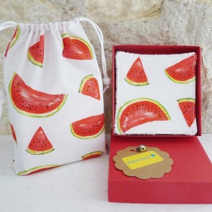 May include: A set of two white cotton makeup remover pads with a watermelon print, packaged in a red box with a brown tag that says "Boutique Chic". The pads are in a white drawstring bag with a watermelon print.