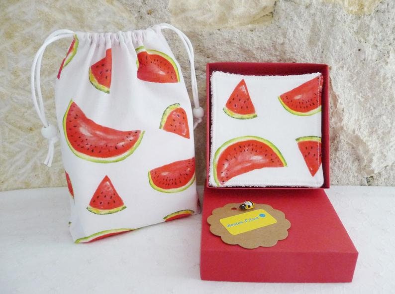 May include: A set of two white cotton makeup remover pads with a watermelon print, packaged in a red box with a brown tag that says "Boutique Chic". The pads are in a white drawstring bag with a watermelon print.
