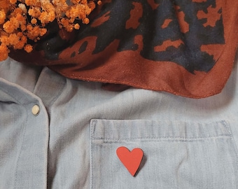 A vibrant red heart-shaped wooden pin, an original clothing accessory, a perfect gift idea to complete your style, glamorous and chic