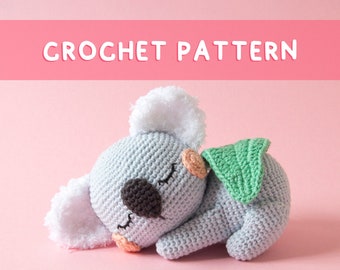 May include: Crochet pattern for a sleeping koala amigurumi toy. The koala is gray with white fur on its ears and a green eucalyptus leaf. The pattern is downloadable as a PDF file.