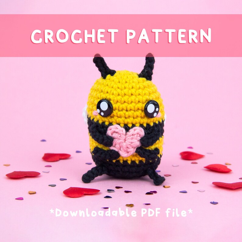 May include: Crochet pattern for a cute bee holding a pink heart. The bee is yellow and black with big black eyes. The pattern is downloadable as a PDF file.