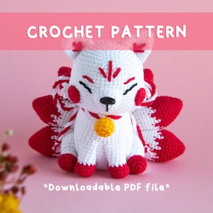 Peut inclure: Un renard blanc et rouge au crochet avec un collier à clochette jaune. Le renard a des accents rouges sur les oreilles, les joues et les pieds. Le texte "CROCHET PATTERN" et "*Downloadable PDF file*" est inclus.