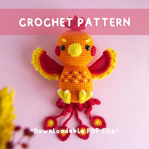 Könnte beinhalten: Ein gehäkeltes Phönix-Spielzeug in Orange-, Rot- und Gelbtönen, mit schwarzen Augen und einem gelben Schnabel. Der Text "CROCHET PATTERN" wird über dem Spielzeug angezeigt. Der untere Teil des Bildes enthält den Text "*Downloadable PDF file*".