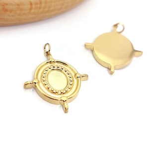 Peut inclure: Deux pendentifs dorés en forme de boussole. L'un présente un centre ovale entouré d'une bordure perlée et quatre extensions. L'autre est un cercle doré avec trois extensions. Idéal pour la création de bijoux.