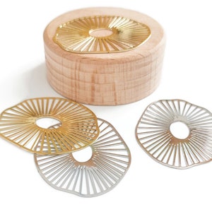 Peut inclure: Trois cercles décoratifs en métal avec un motif en forme de soleil. Deux cercles sont argentés et un est doré.