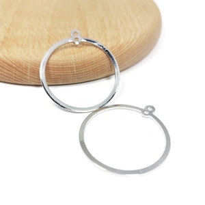 May include: Two silver hoop earrings with a small loop at the top for attaching a pendant or charm.