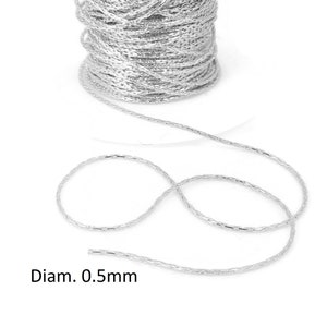Peut inclure: Une bobine de chaîne argentée de 0,5 mm de diamètre. La chaîne est composée de petits éléments métalliques liés.