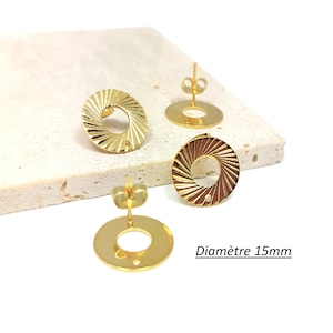 Op de afbeelding: Twee gouden oorbellen met een rond ontwerp. De oorbellen hebben een getextureerd, zonnestralenpatroon en een klein gaatje in het midden. De oorbellen hebben een diameter van 15 mm. Diametre 15mm