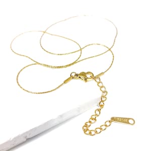 Peut inclure: Un collier en chaîne dorée avec un fermoir à ressort et une chaîne d'extension. La chaîne est délicate et a une finition texturée fine.