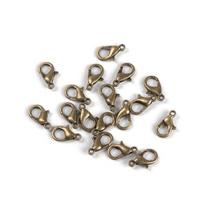 May include: A group of 18 antique gold-toned metal lobster claw clasps. These clasps are commonly used for jewelry making and crafting.