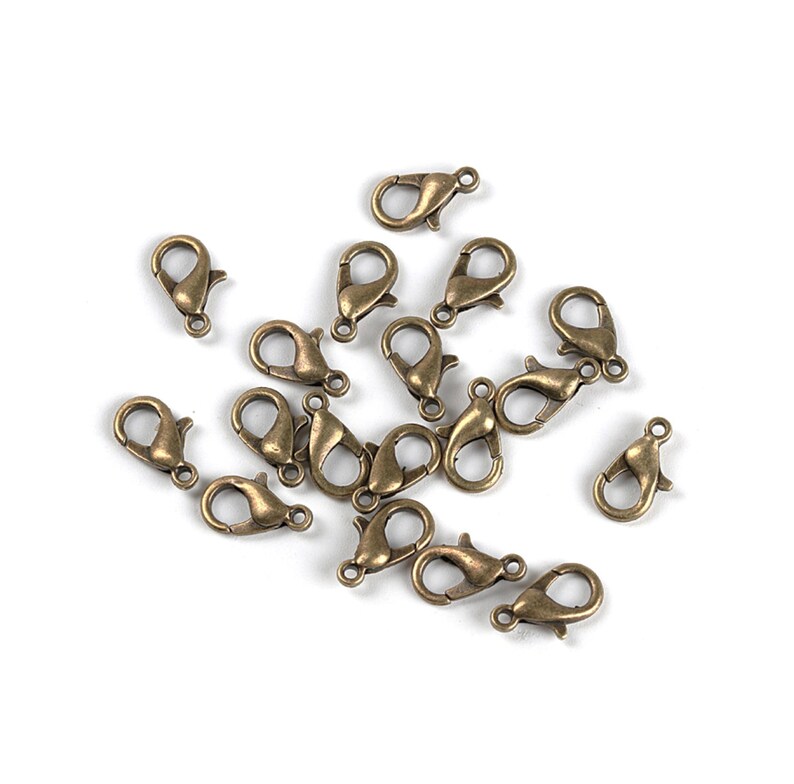 May include: A group of 18 antique gold-toned metal lobster claw clasps. These clasps are commonly used for jewelry making and crafting.