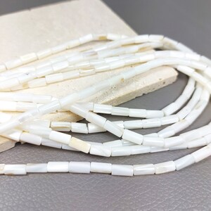 May include: A strand of white rectangular shell beads. The beads are smooth and have a slight iridescent sheen.
