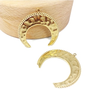 Op de afbeelding: Twee goudkleurige halve maanvormige metalen bedels met een getextureerd oppervlak en een parelrand.