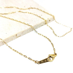 Peut inclure: Un collier chaîne en or avec une fermeture à fermoir. La chaîne est composée de petits maillons rectangulaires. L'étiquette sur le fermoir indique "14K".