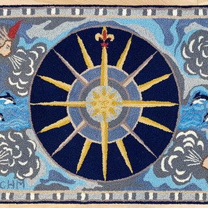 K&ouml;nnte beinhalten: Ein blauer und goldener Teppich mit einem Sonnenstrahl-Design in der Mitte. Der Sonnenstrahl ist von vier Wolken mit Gesichtern und vier Delfinen umgeben, die im Wasser schwimmen. Der Teppich hat einen grauen und wei&szlig;en Rand.