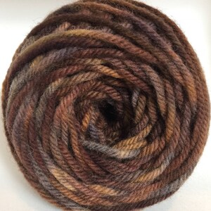 May include: A ball of brown, orange, and gray yarn. The yarn is wound into a tight coil.