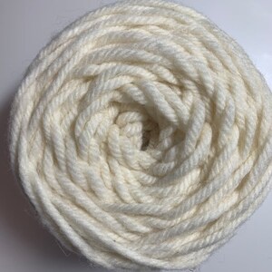 May include: A close-up of a white yarn ball, showing the tightly wound yarn in a spiral pattern.