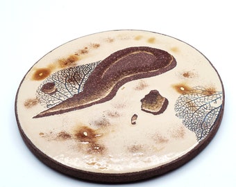 Underside of flat round beige fault in enamelled lava of the volcanoes of Auvergne and touches of fine gold Diam: 28 cm