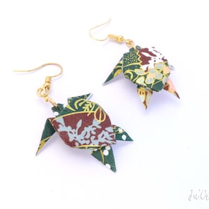 Puede incluir: Un par de pendientes de origami con un diseño estampado en verde, marrón y blanco. Los pendientes están hechos de papel y tienen ganchos de color dorado.