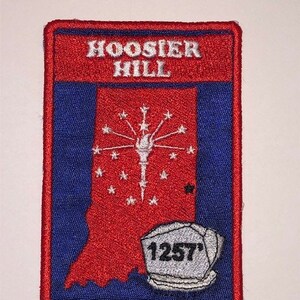 May include: Red, white, and blue embroidered patch with the text "Hoosier Hill" and an outline of the state of Indiana with a firework design and the number "1257" in a white circle.