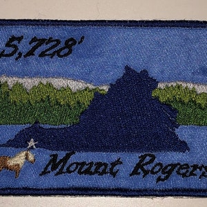 Könnte beinhalten: Ein blauer gestickter Aufnäher mit einer Silhouette eines Berges, einem kleinen Pferd und dem Text "5,728' Mount Rogers".