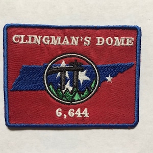 Könnte beinhalten: Ein roter gestickter Aufnäher mit blauem Rand. Der Aufnäher zeigt eine weiße Umrandung des Bundesstaates Tennessee mit einem Kreis in der Mitte. Der Kreis enthält eine schwarze Umrandung des Logos des Great Smoky Mountains National Park mit weißen Sternen und einer grünen Bergkette. Der Text "CLINGMAN'S DOME" befindet sich oben auf dem Aufnäher und "6,644" unten.