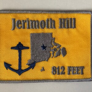 May include: Embroidered patch with a yellow background and gray border. The patch features the text "Jerimoth Hill", a gray outline of Rhode Island, a blue anchor, and the text "812 FEET".