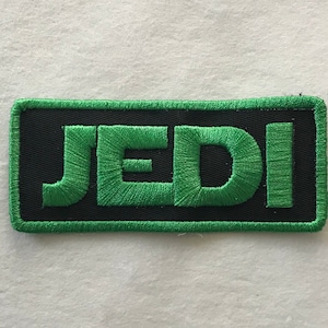 May include: Green embroidered patch with the word "JEDI" in black outlined letters.