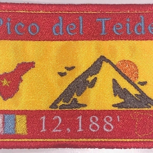 Op de afbeelding: Een geborduurde patch in rood, geel en wit met de tekst "Pico del Teide" en een gestileerd bergbeeld. De patch bevat ook een klein beeld van de Canarische Eilanden en de tekst "12,188'" in wit.