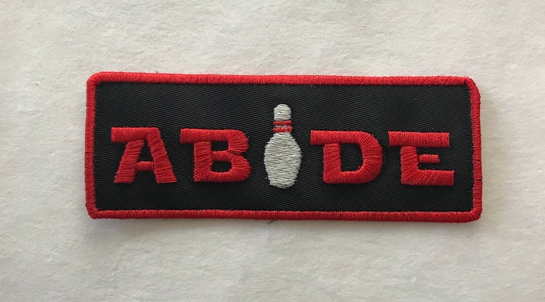 May include: Black embroidered patch with red stitching and the word "ABIDE" in red letters. A white bowling pin is centered between the letters.