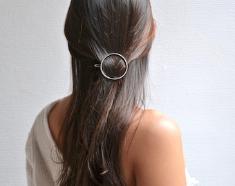 Minimalistische Kreisspange. Haarschmuck, golden, silberner Clip, kreisförmiger Ring. Feines, raffiniertes, boho, glänzendes, schlichtes Accessoire.