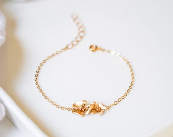 May include: A delicate gold chain bracelet with a floral design. The bracelet features a cluster of small, gold flowers.