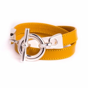 Peut inclure: Un bracelet double tour en cuir jaune avec une fermeture à boucle argentée.