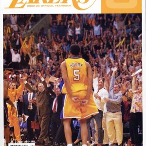Op de afbeelding: De cover van het officiële jaarboek van de Lakers 2002-03. Een basketballer in een geel shirt met de naam "Horry" en nummer "5" op de rug springt op het veld. De achtergrond toont een juichende menigte. De tekst "LAKERS" is zichtbaar.