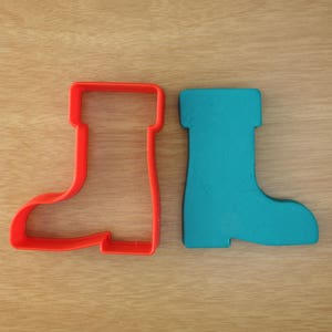 May include: Two cookie cutters shaped like boots. The boot on the left is red and the boot on the right is blue.