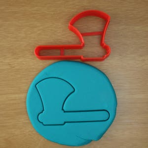 May include: A red plastic cookie cutter shaped like an axe. A blue fondant cookie is shown with an axe shape cut out of it.